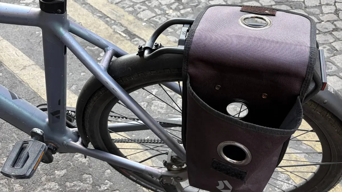 Grey Dance-branded pannier screwed onto the rear rack of a Dance bike, open, with the carbon belt drive and kickstand visible